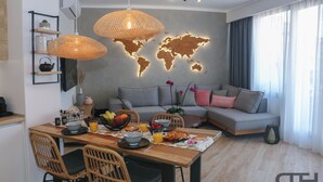 Ett modernt vardagsrum med en matplats, inrett med en soffa, flätade stolar, ett matbord i trä och en världskarta på väggen.