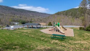 Un parque con un área de juegos, mesas de picnic y un refugio.
