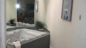 Un baño con bañera, espejo y un cuadro en la pared.
