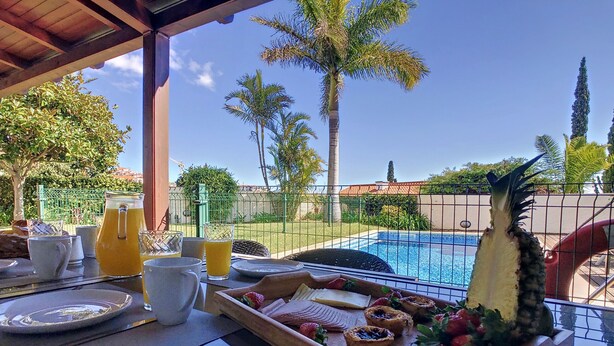 Une table de petit-déjeuner avec un plateau de viennoiseries, une carafe de jus d’orange et un verre d’eau.