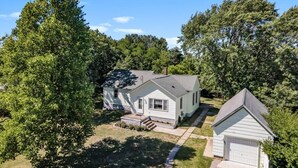 A two-story house with a garage, surrounded by trees. - Clean and Modern Home near Lk MI (Manistee)