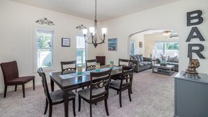 A dining area with a table, chairs, and a chandelier. There is a sofa and a coffee table in the background. - Clean and Modern Home near Lk MI (Manistee)