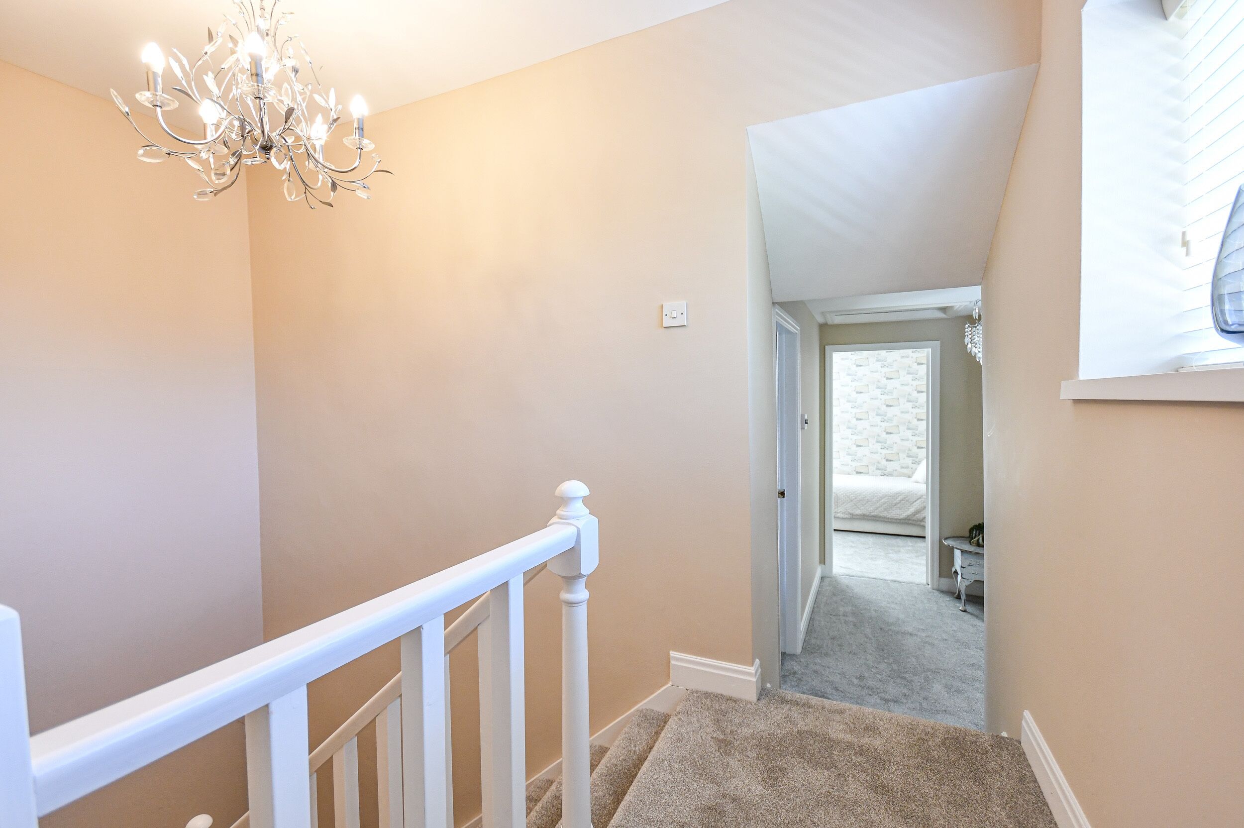 A staircase with a white railing leading to a bedroom with a bed and a nightstand.
