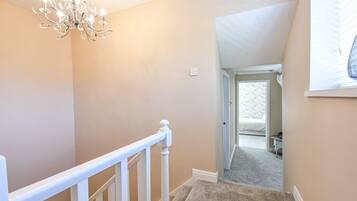 A staircase with a white railing leading to a bedroom with a bed and a nightstand.