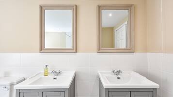 A bathroom with two sinks, a toilet, and a mirror above each sink.