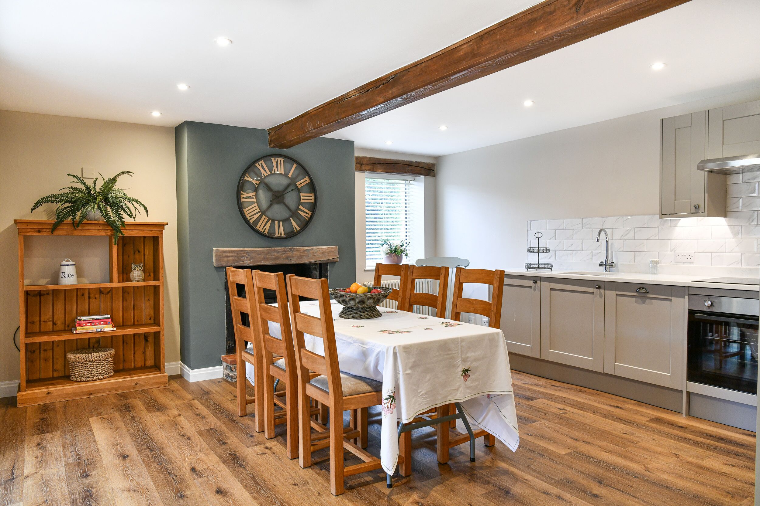 A dining area with a wooden table, chairs, and a clock on the wall.