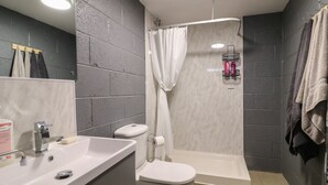 A modern bathroom with a white sink, toilet, and shower. - The Pod at Bank House Farm (Uttoxeter)