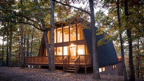 Een chalet met een houten terras, grote ramen en een trap naar de ingang.