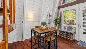 Een eethoek met een houten tafel en stoelen, een potplant en een bankje bij de deur.