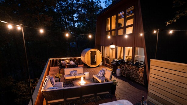 Een terras buiten met een hottub, zitgedeelte en lichtjes.
