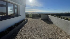A modern building with a gravel patio and a view of the countryside. - 18th century farmhouse on the foothills of Wicklow (Gorey)