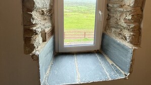 A small, narrow room with a single door leading to a view of a green field. - 18th century farmhouse on the foothills of Wicklow (Gorey)