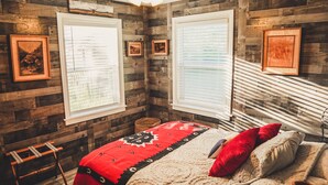 Een kamer met houten wanden, een bed met een rode deken en wanddecoraties.