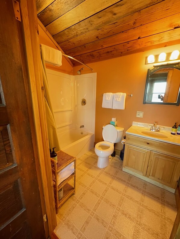 Baño de cabaña de madera con bañera, inodoro y tocador.