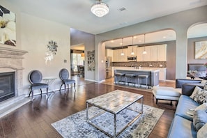 A spacious living room with a fireplace, seating area, and a kitchen with bar stools.