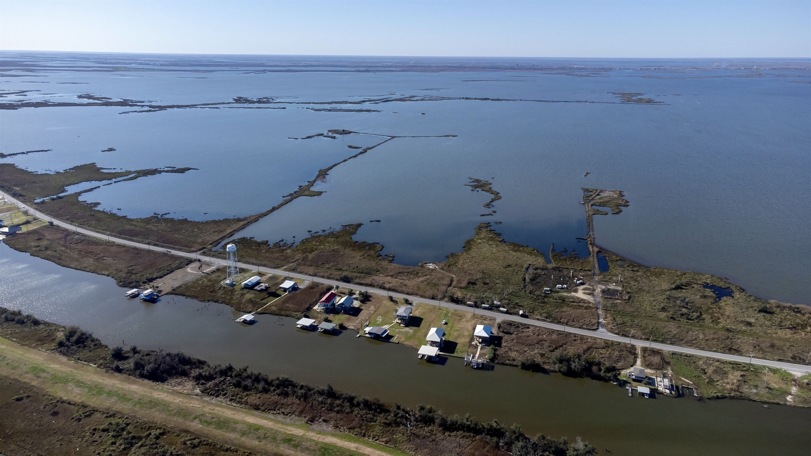 Vue aérienne d’une zone côtière avec un port de plaisance, des bateaux et des bâtiments le long de la côte.