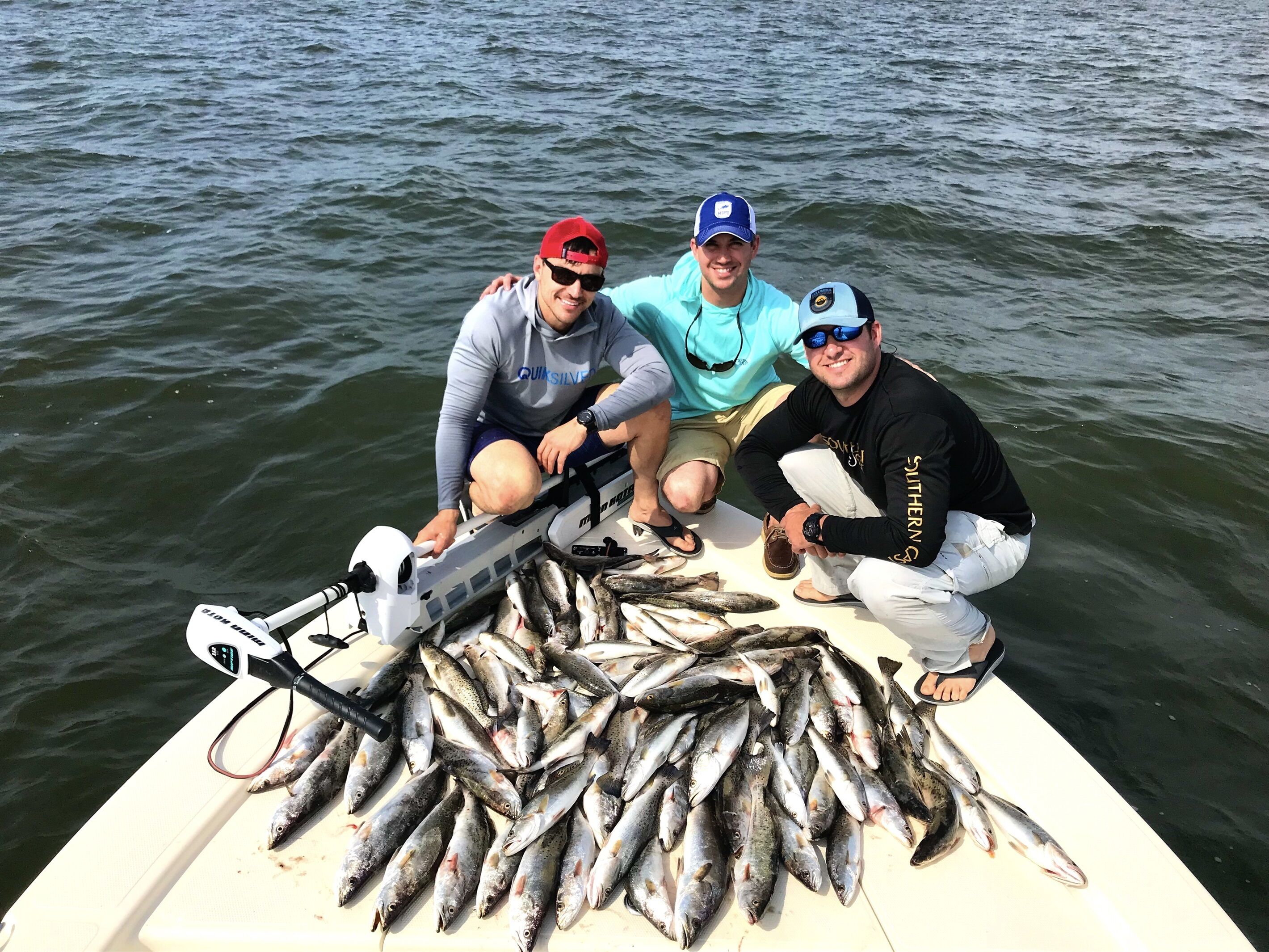Trois personnes se trouvent dans un bateau, entourées d’une grande quantité de poissons.