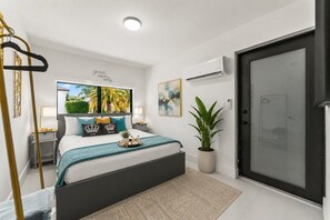 A modern bedroom with a bed, bedside tables, a hanging chair, a potted plant, and a door. - Majestic Mansion - Heated Pool, BBQ, Playground (Miami)