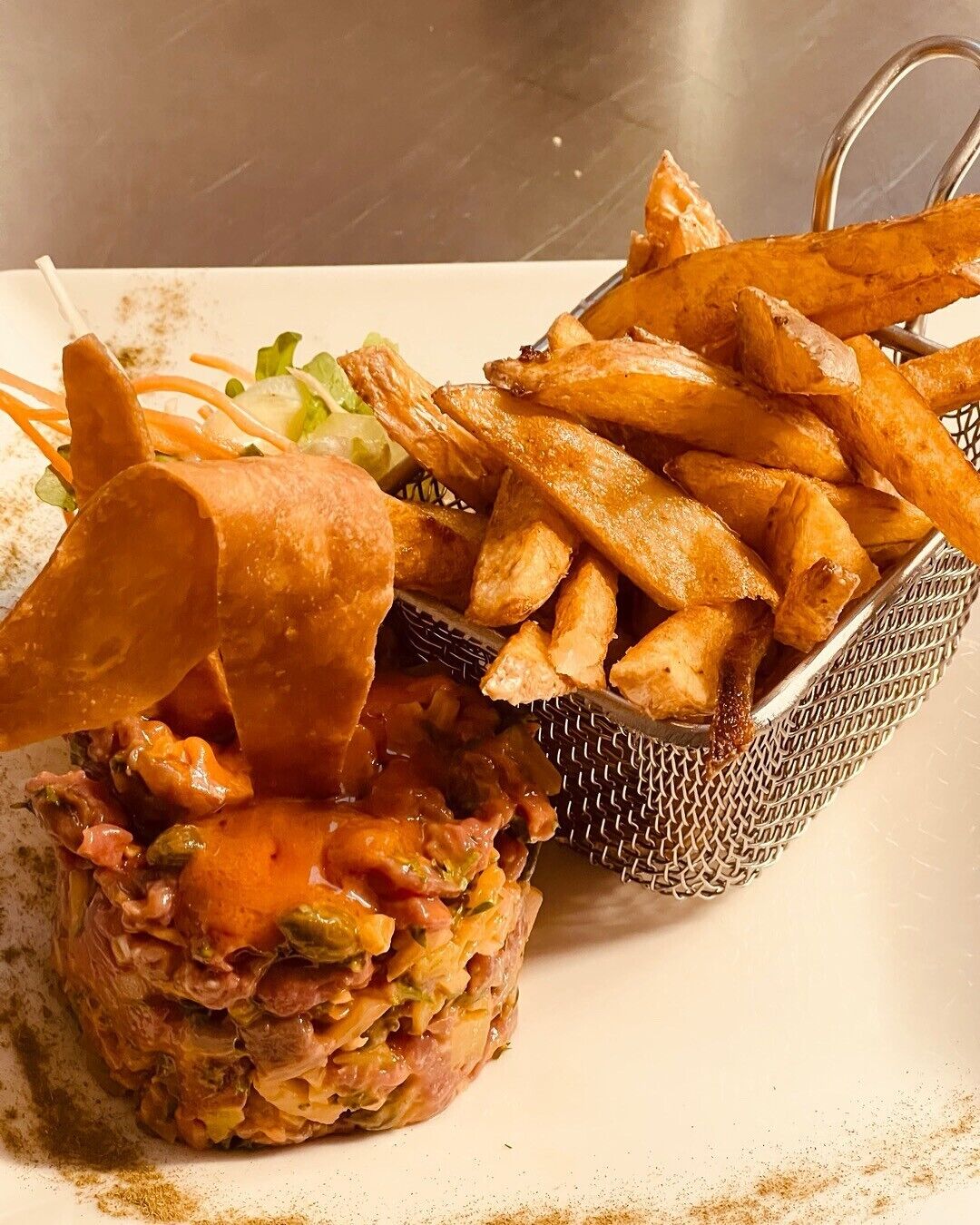 A dish with a meat patty, fries, and a side salad.