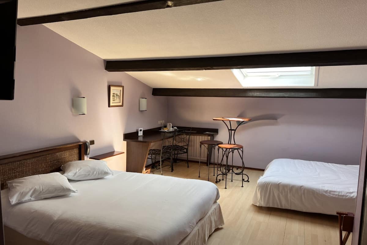 Une chambre avec deux lits, un bureau, une chaise et une petite table.