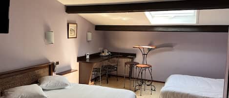 Habitación de hotel con dos camas, kitchenette, un pequeño comedor y tragaluz.