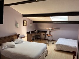 Habitación de hotel con dos camas, kitchenette, un pequeño comedor y tragaluz.