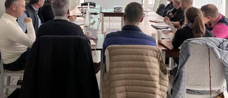 Un salón de conferencias con una pantalla de presentación, paredes blancas y un proyector.
