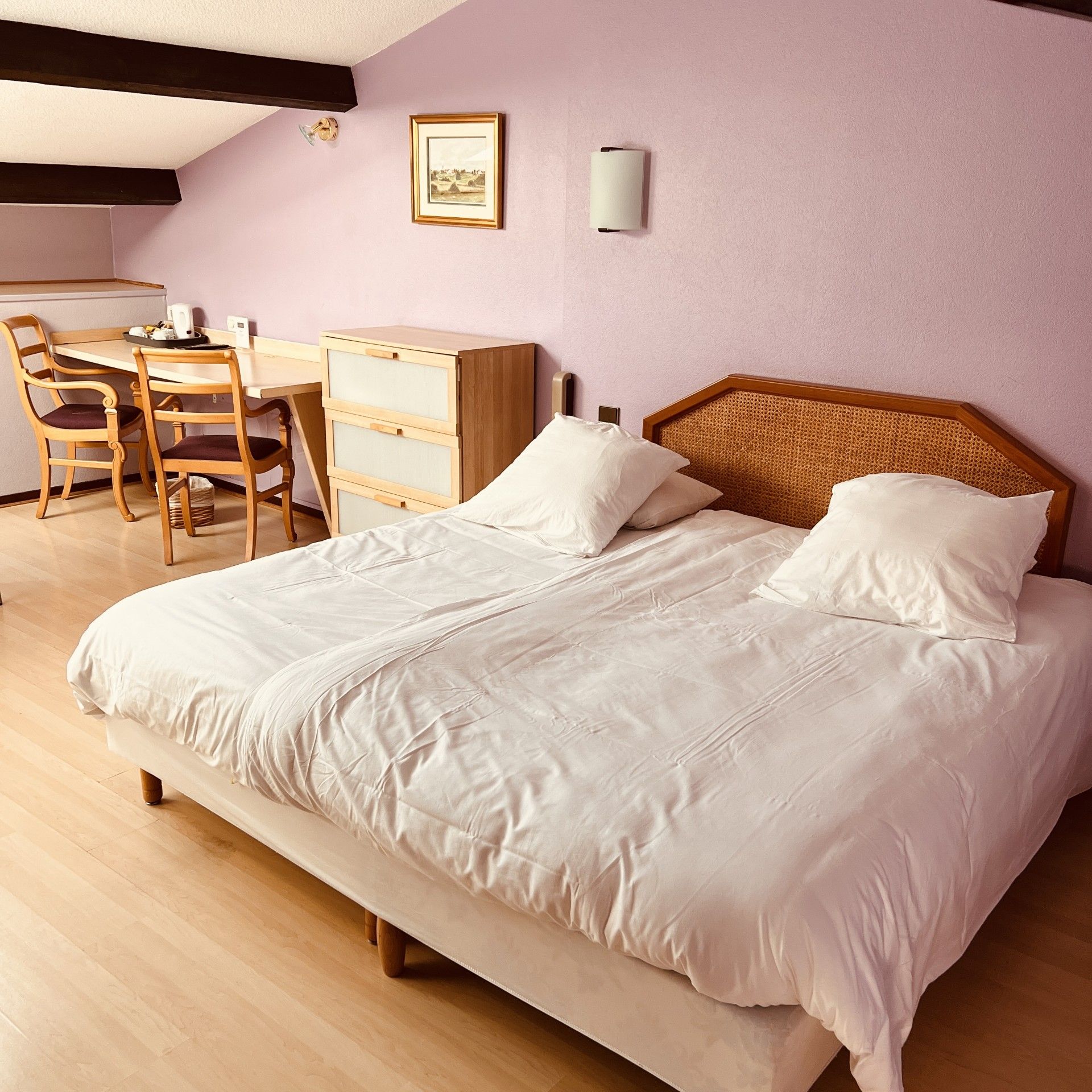 A bedroom with a bed, a desk, and chairs.