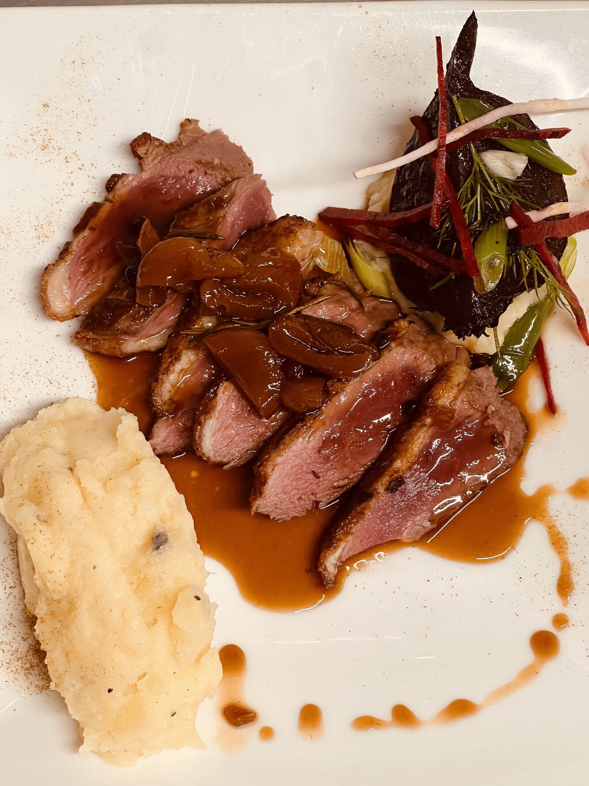 Ein Teller mit geschnittenem Fleisch, Kartoffelpüree und einem Beilagensalat.