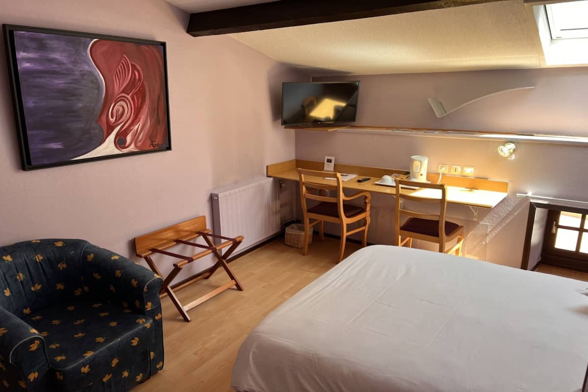 Une pièce comprenant un lit, un bureau avec une chaise, une télévision et un tableau accroché au mur.
