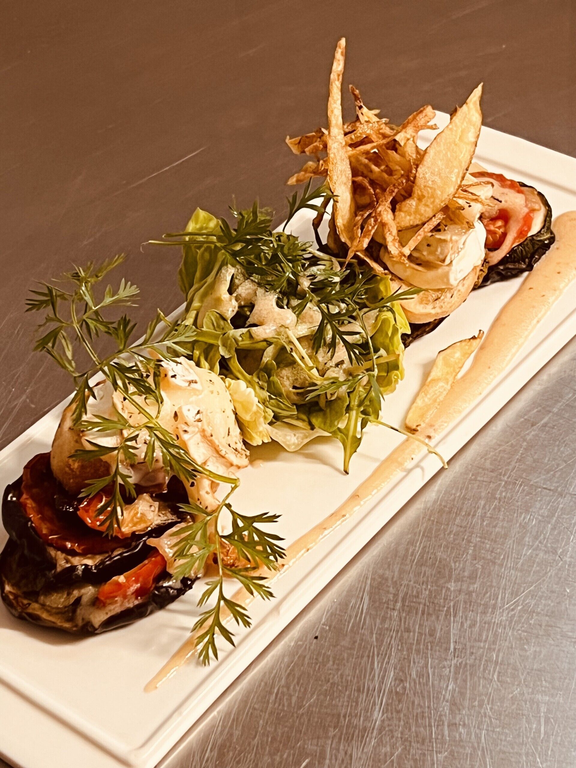 A plated dish with various food items, including a stuffed vegetable, a salad, and some crispy elements.