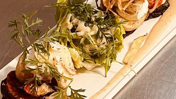 A plated dish with various food items, including a stuffed vegetable, a salad, and some crispy elements.