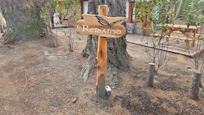 Un panneau indicateur en bois portant les inscriptions « El Retamo » et « Cabanas », entouré d’arbres et agrémenté d’une terrasse en bois.