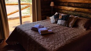 A bed with a quilted bedspread, several pillows, and a folded towel on a wooden floor.
