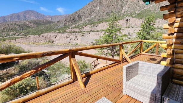 A wooden deck with a metal railing overlooking a mountainous landscape.