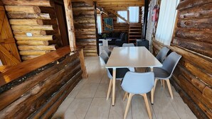 A log cabin interior with a dining table and chairs, a staircase, and a sofa.