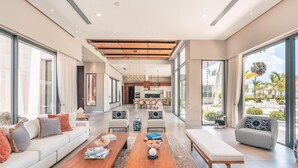 A spacious living area with a sofa, two wooden coffee tables, and a bench.