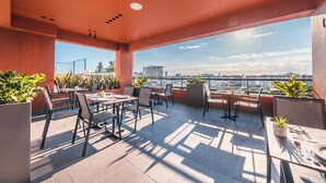Terraço no telhado com área de estar ao ar livre, plantas em vasos e vista para a cidade.