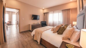A hotel room with a large bed, a desk, a chair, a television, and a view of the outside through the window. - Breakfast Included at Regatta Living 301 (Santo Domingo)
