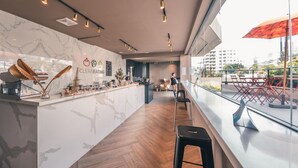 A modern bar area with a marble countertop, wooden flooring, and a view of the city through large windows.