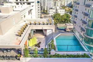 A rooftop pool area with a pool, seating, and potted plants.