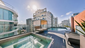 A rooftop pool area with a glass balustrade, a sun lounger, and a seating area with a canopy. - Flat in Regatta II With Breakfast Included 203 (Santo Domingo)