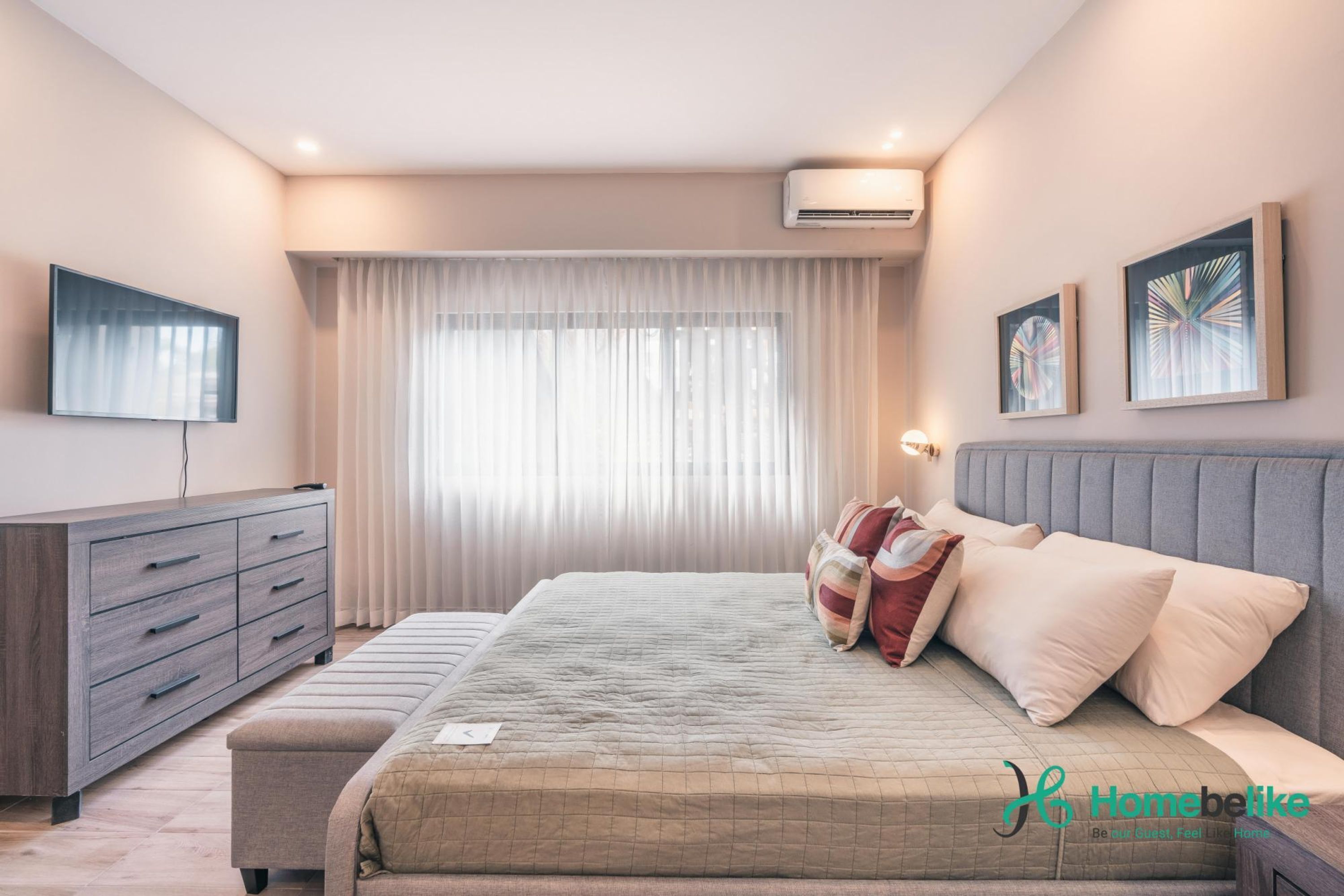A bedroom with a bed, a dresser, a window with curtains, and wall-mounted artwork.