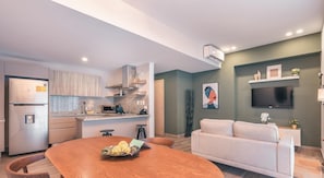 Cozy living space with a kitchen and living area, featuring an oven, flat-screen TV, and dining table.