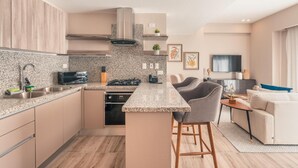 A modern kitchen with granite countertops, stainless steel appliances, and a central island with bar stools. - Regatta Living II - 406 (Santo Domingo)