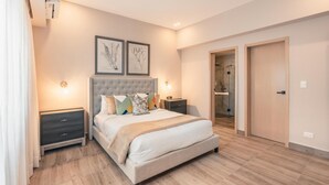 A bedroom with a large bed, two bedside tables, a wardrobe, and a shower area. - Regatta Living II - 406 (Santo Domingo)