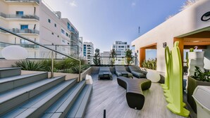 A rooftop terrace with outdoor seating, steps leading up to the terrace, and a view of surrounding buildings. - Regatta Living II - 406 (Santo Domingo)