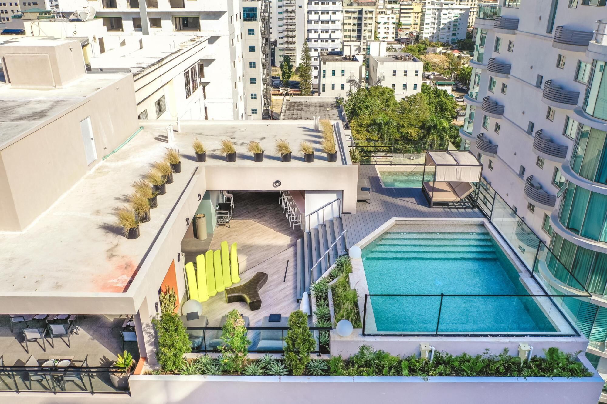 A rooftop pool area with a pool, seating, and potted plants.