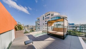 A rooftop terrace with a pool, a sunbed, and a view of a modern building. - Regatta Living II - 703 (Santo Domingo)