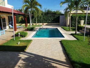 Relax by the pool surrounded by lush greenery and palm trees.